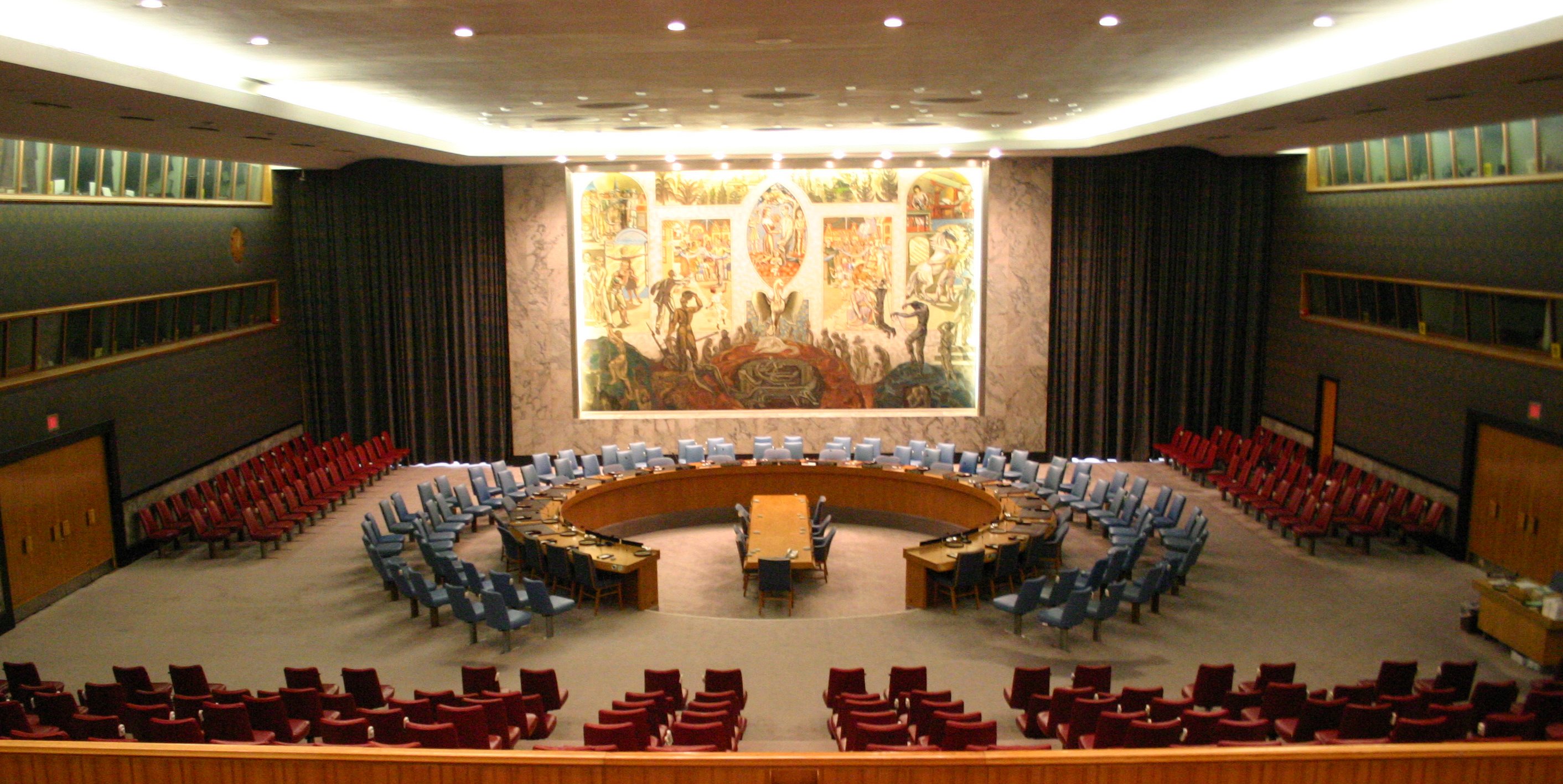 The United Nations Security Council chamber in New York, showing the curving rows of seats, the long table and the Per Krohg mural