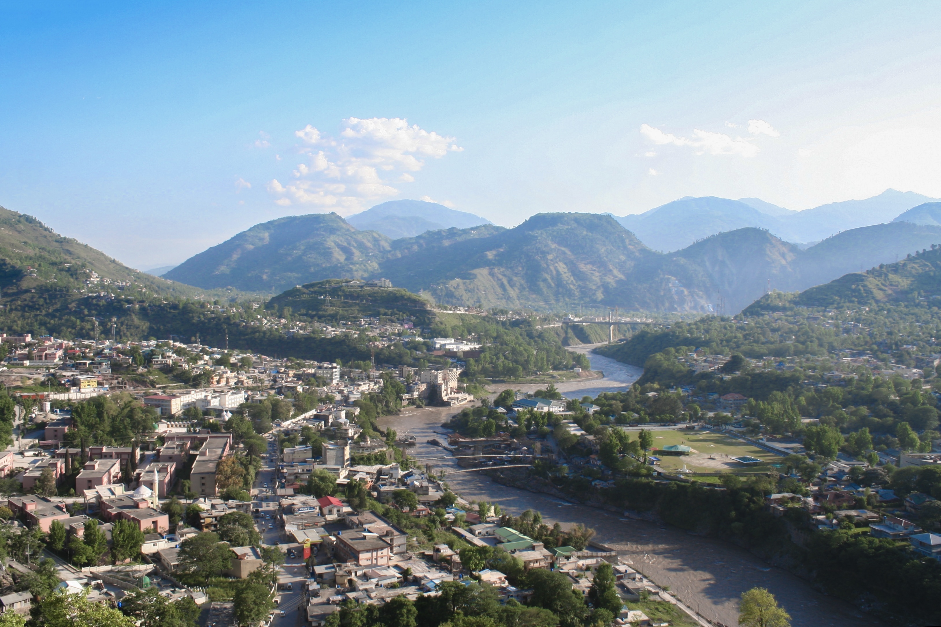 A view over Muzaffarabad city in Azad Jammu and Kashmir, with a river in the foreground.