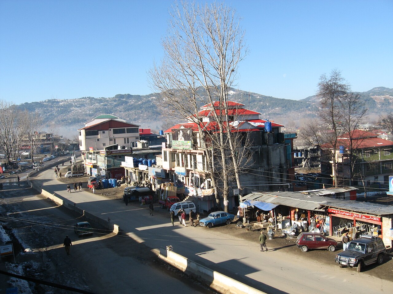 A view of Mong Road in Rawalakot, Azad Jammu and Kashmir, with buildings and hills.
