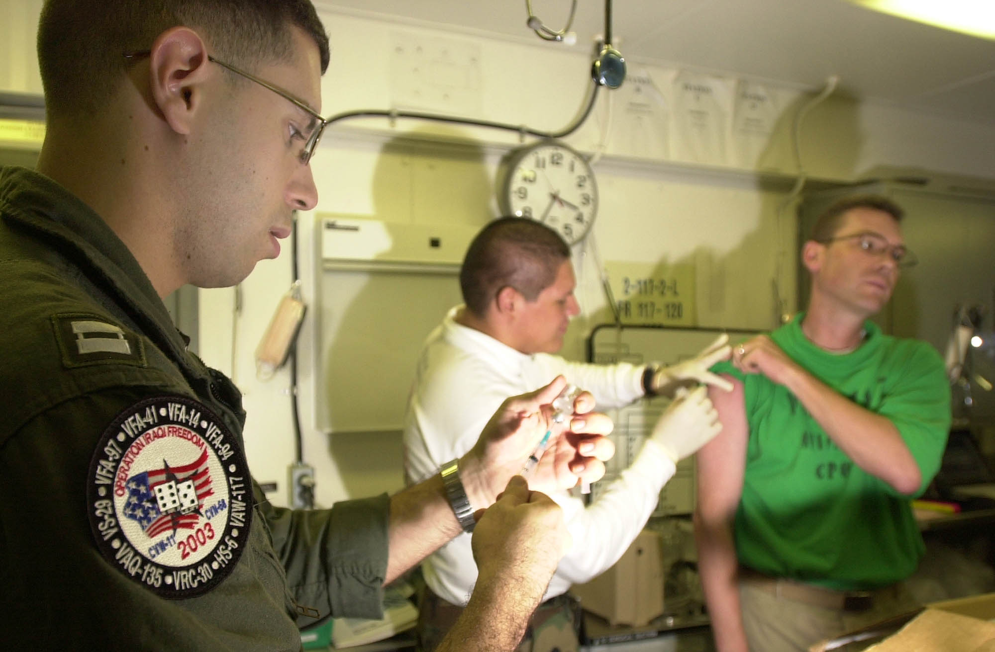Medical personnel preparing syringes before administering vaccinations in a clinical setting.