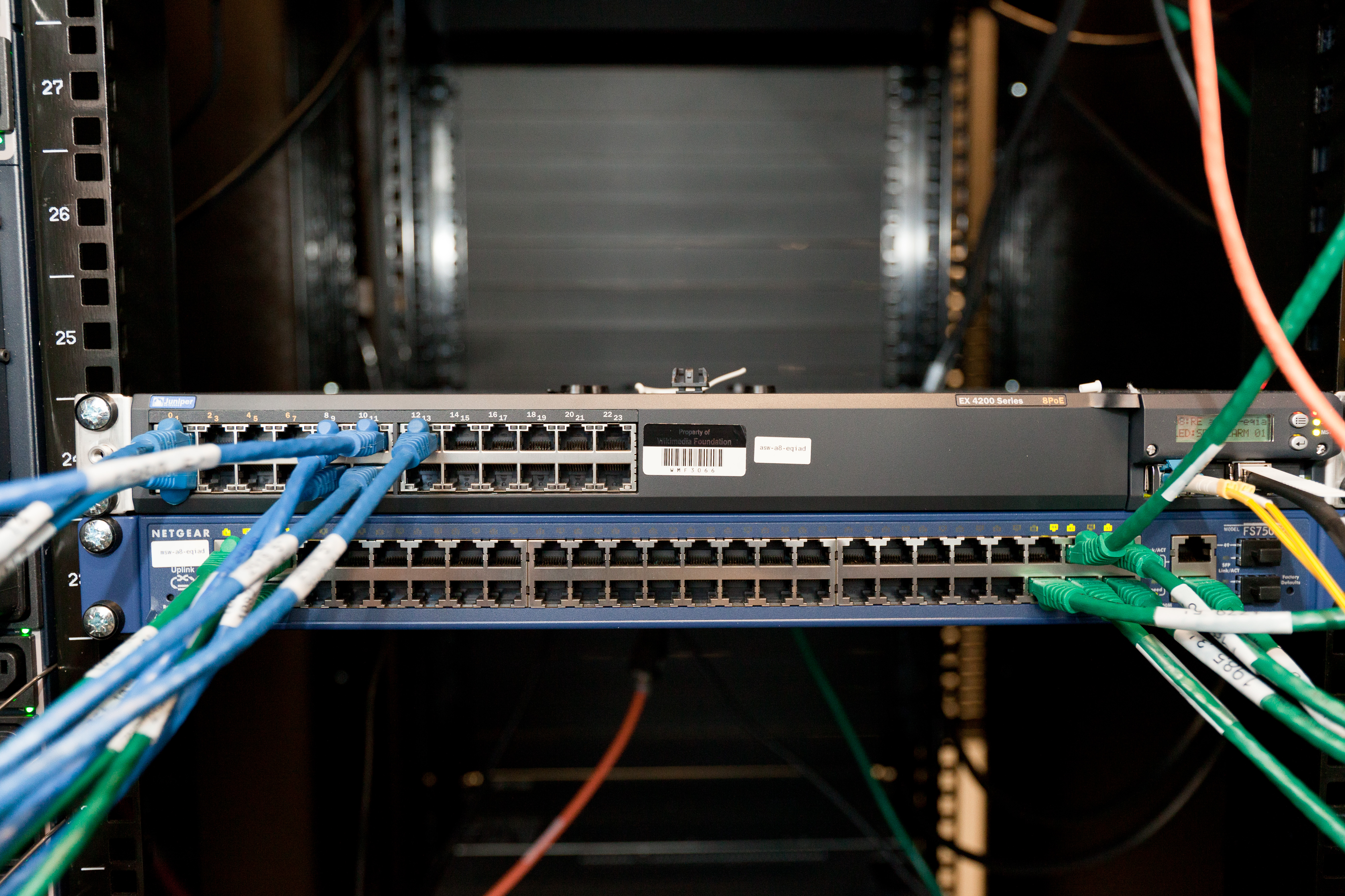 Rows of black rack-mounted network switches with bundled cabling in a server room