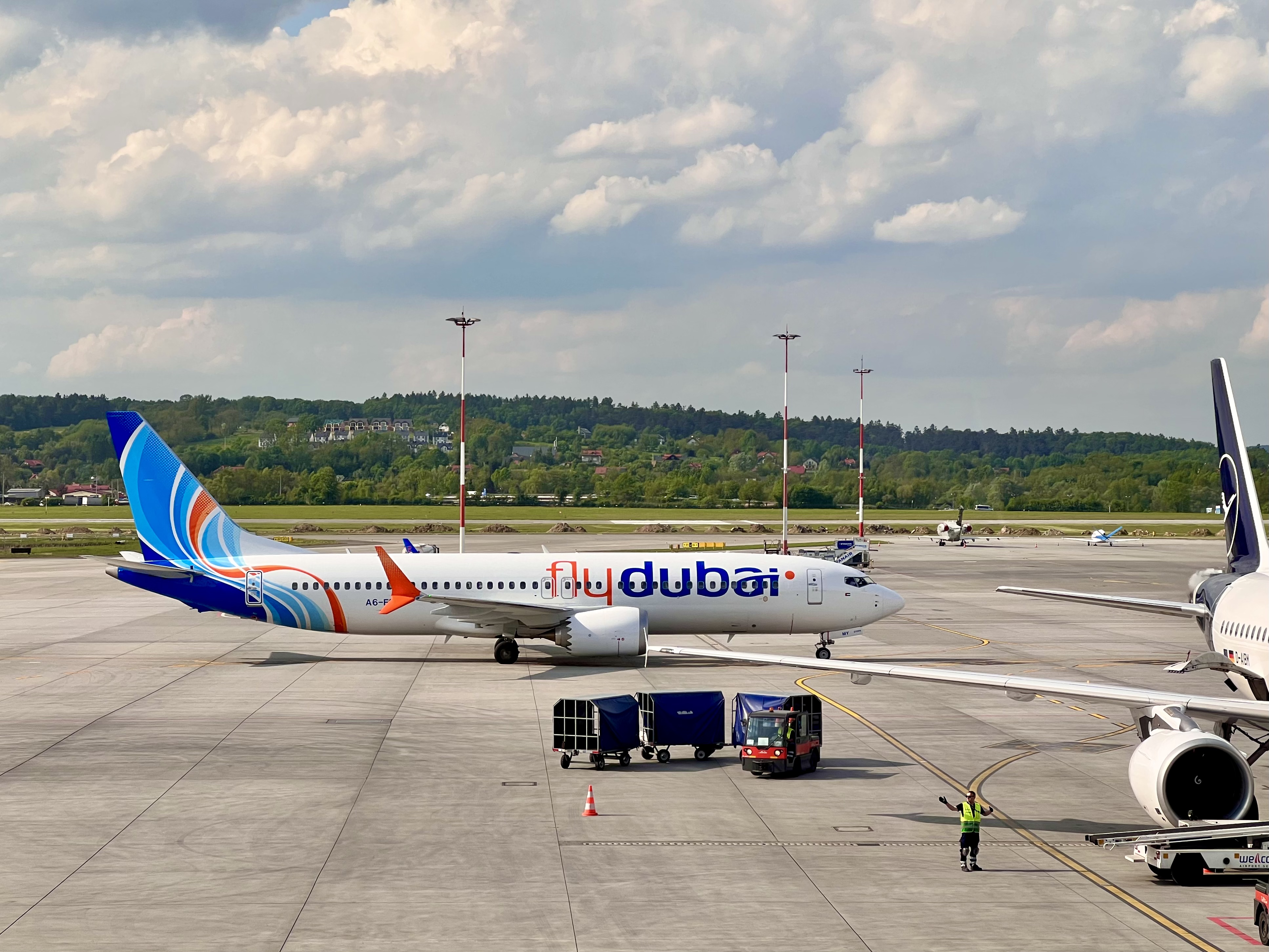 A flydubai Boeing 737 MAX in the airline's blue, orange and white livery parked on an airport apron.