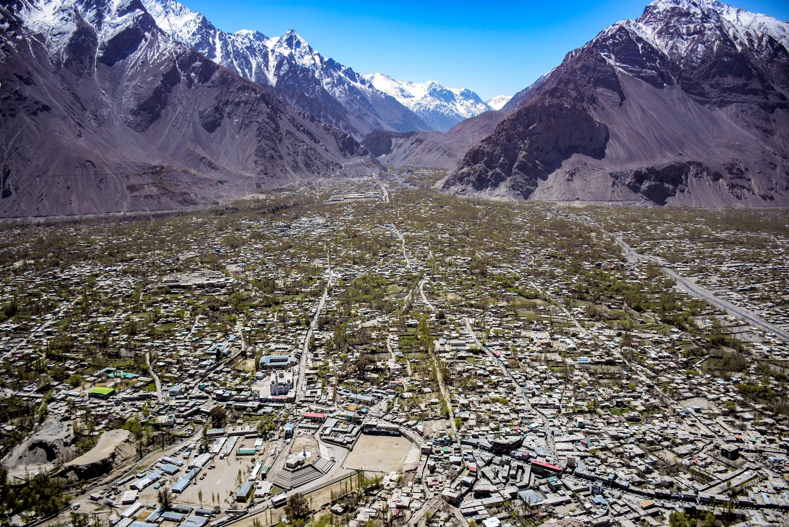 An elevated view of Skardu city in Gilgit-Baltistan, with dense low-rise buildings set against bare mountains.
