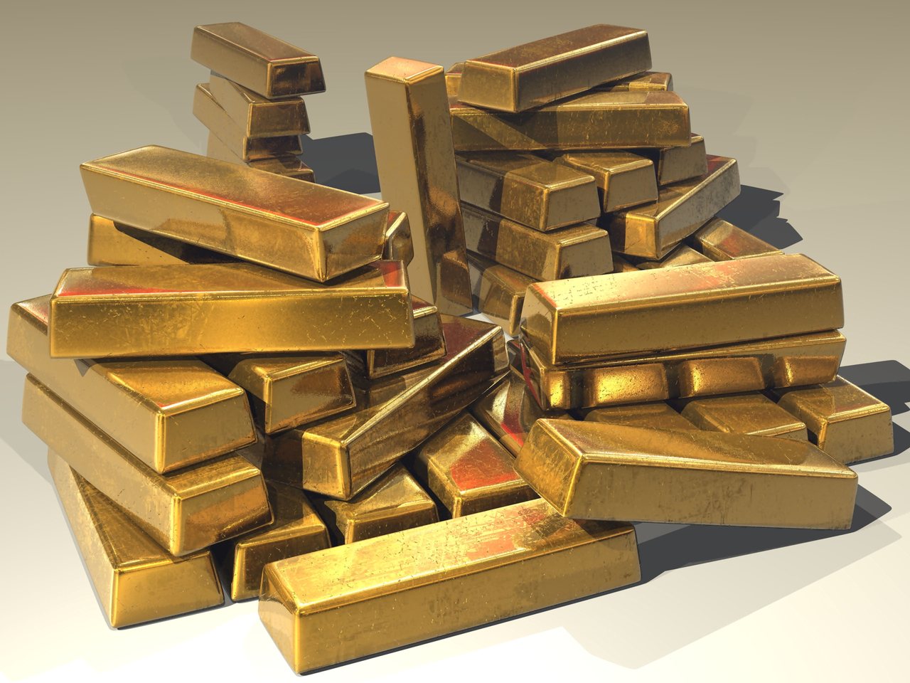 Stacked gold bullion bars with a large gold bar in the foreground under warm light.