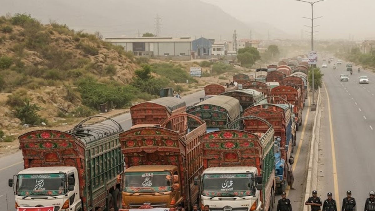 A long line of decorated goods trucks parked along the shoulder of a highway, with police officers standing on the road beside them.