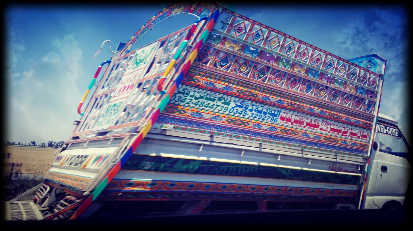 A decorated Pakistani goods truck carrying a load along a road.