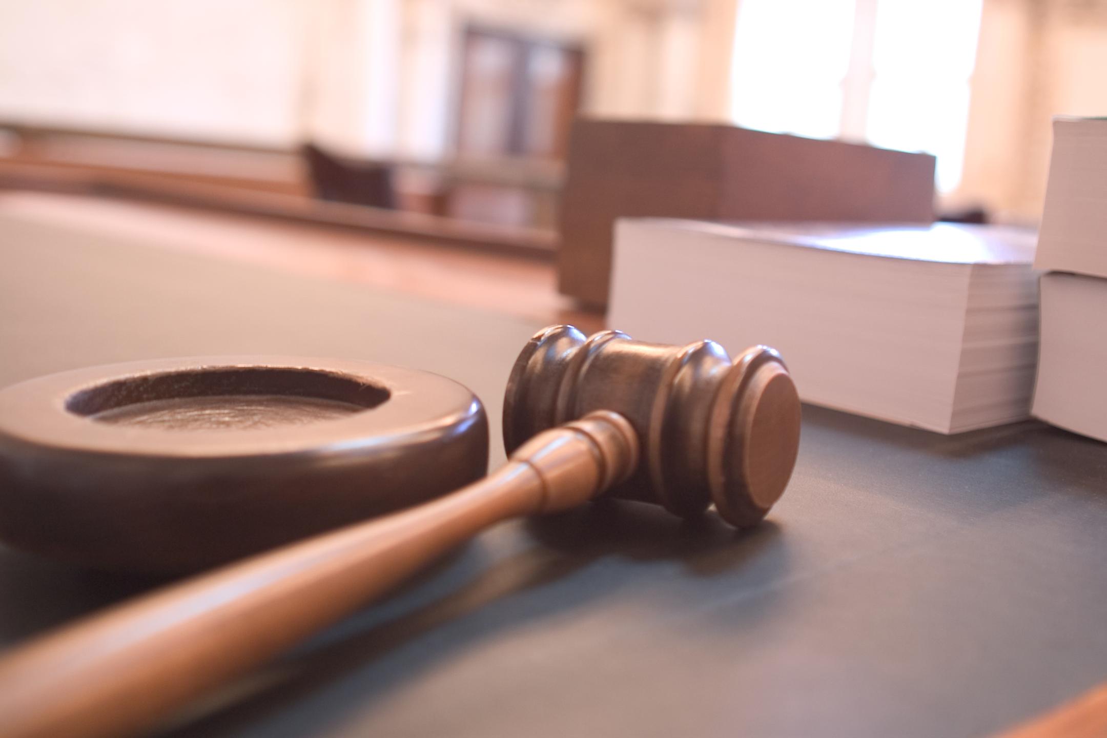 A wooden judge's gavel resting on a round sound block.