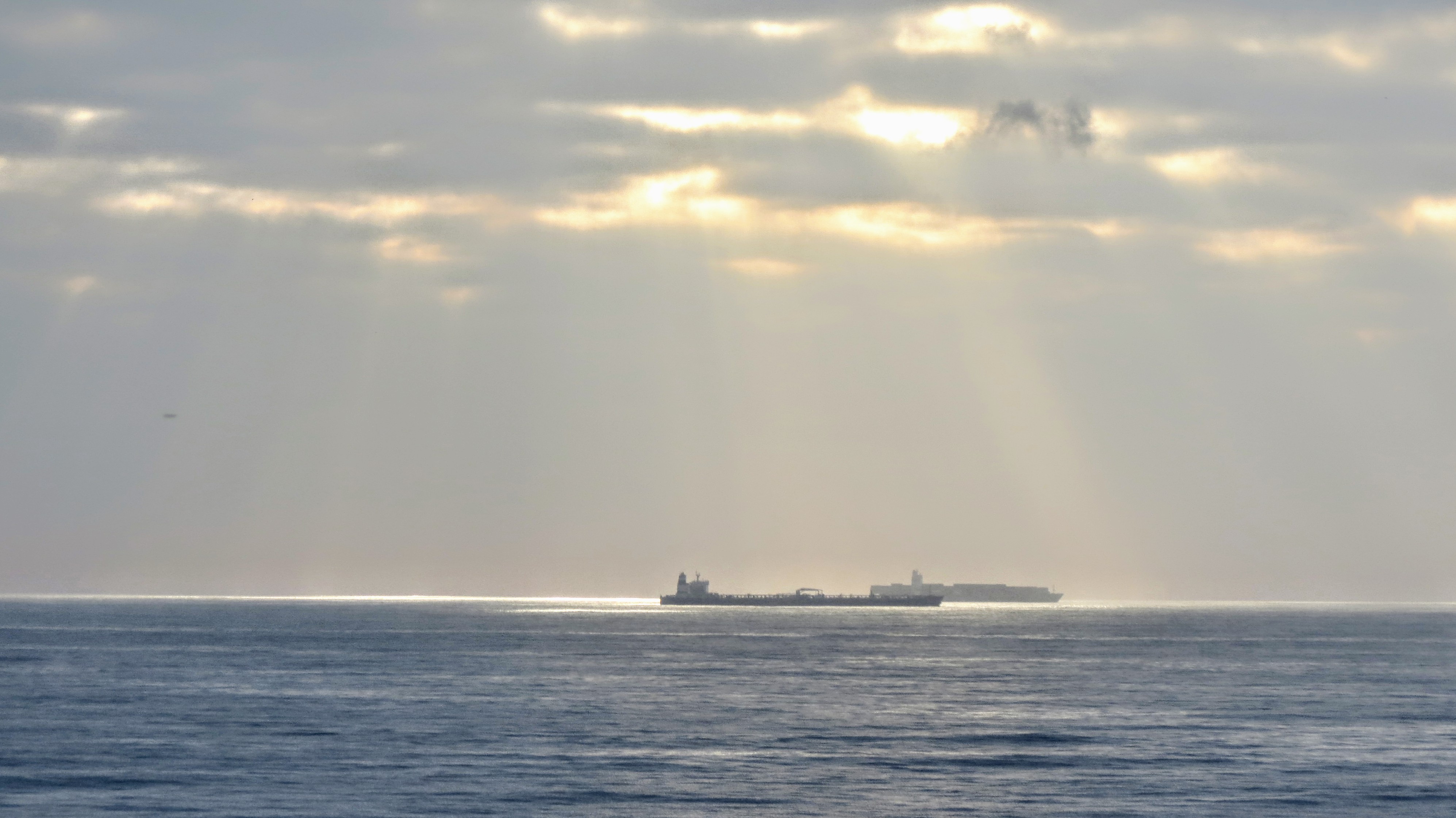 A tanker waiting on the high seas outside Durban harbour at sunrise, with harbour infrastructure in the foreground and a partly cloudy sky above, used as contextual reference for commercial oil tanker operations.