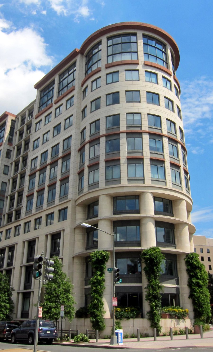 A tall office building with a curved facade rising above a street