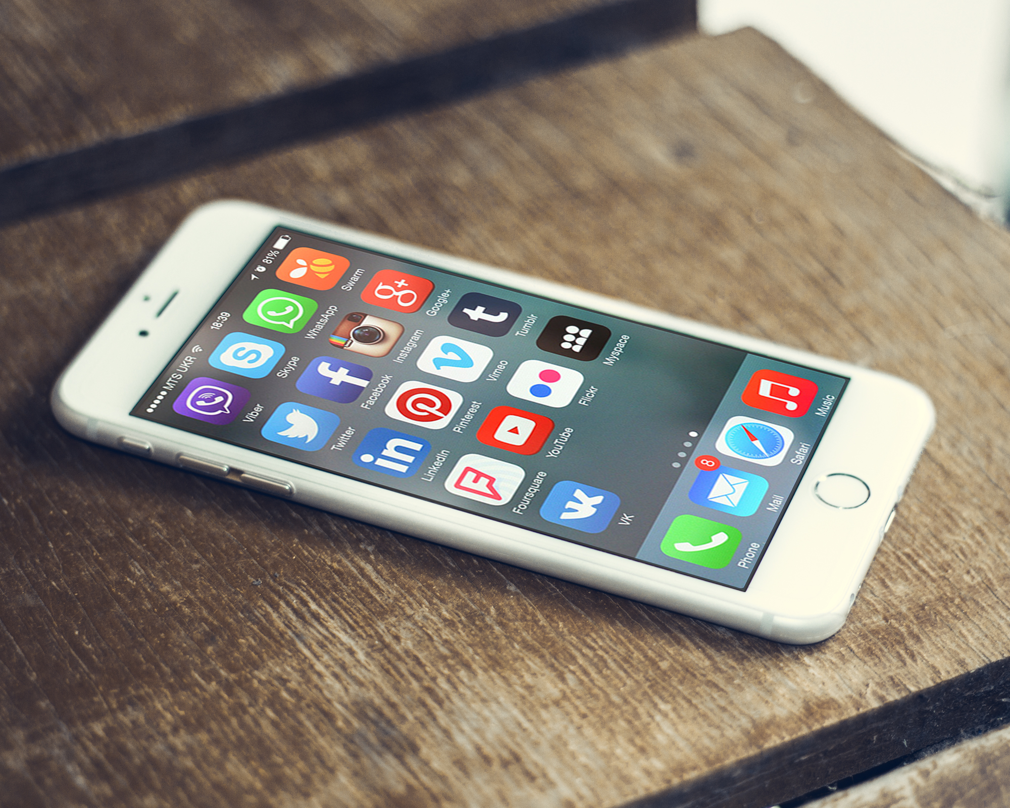 A grid of social media and messaging application icons on the screen of a smartphone held in one hand.