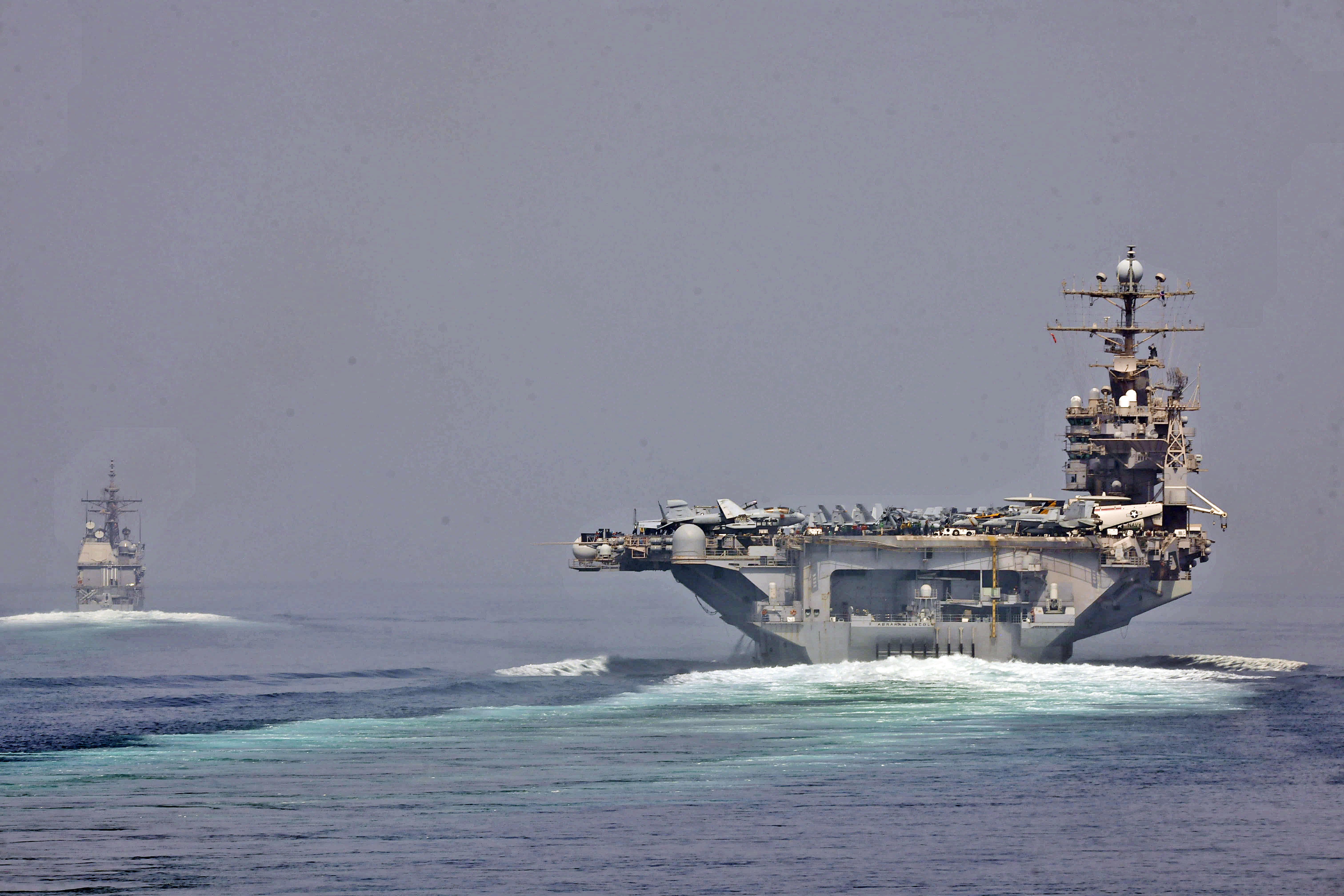 Two US Navy warships, a guided-missile cruiser and an aircraft carrier, transit the Strait of Hormuz