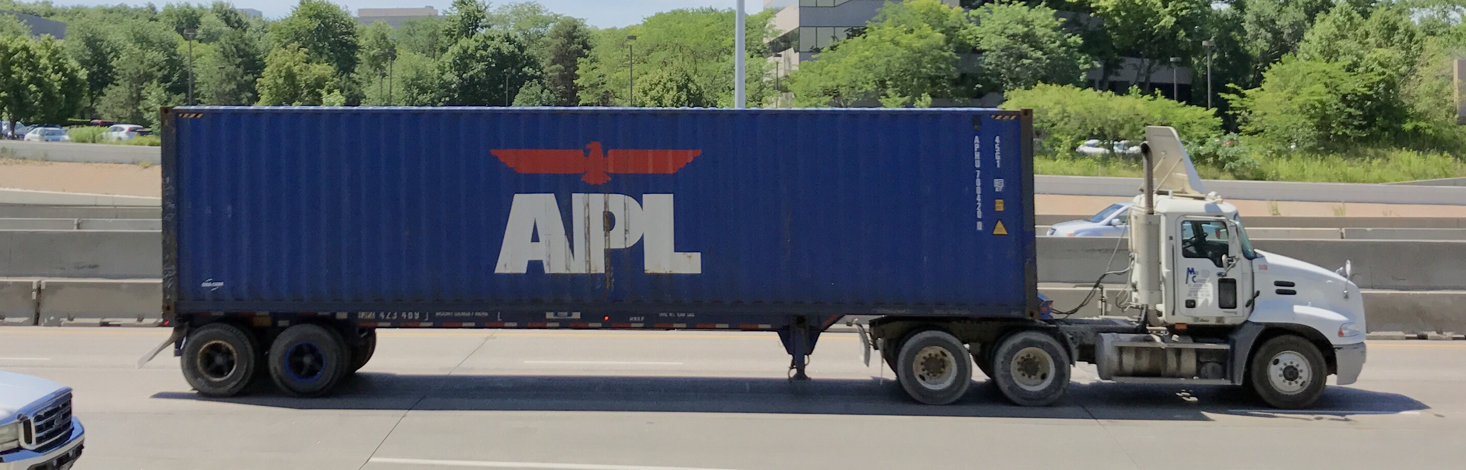 A shipping container mounted on a truck chassis travelling along a multi-lane freeway