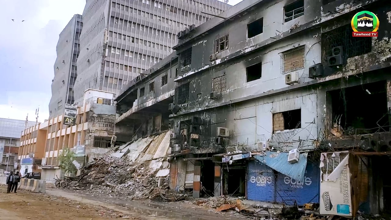 The fire-damaged exterior of Gul Plaza in Karachi, with a collapsed section of the building visible.