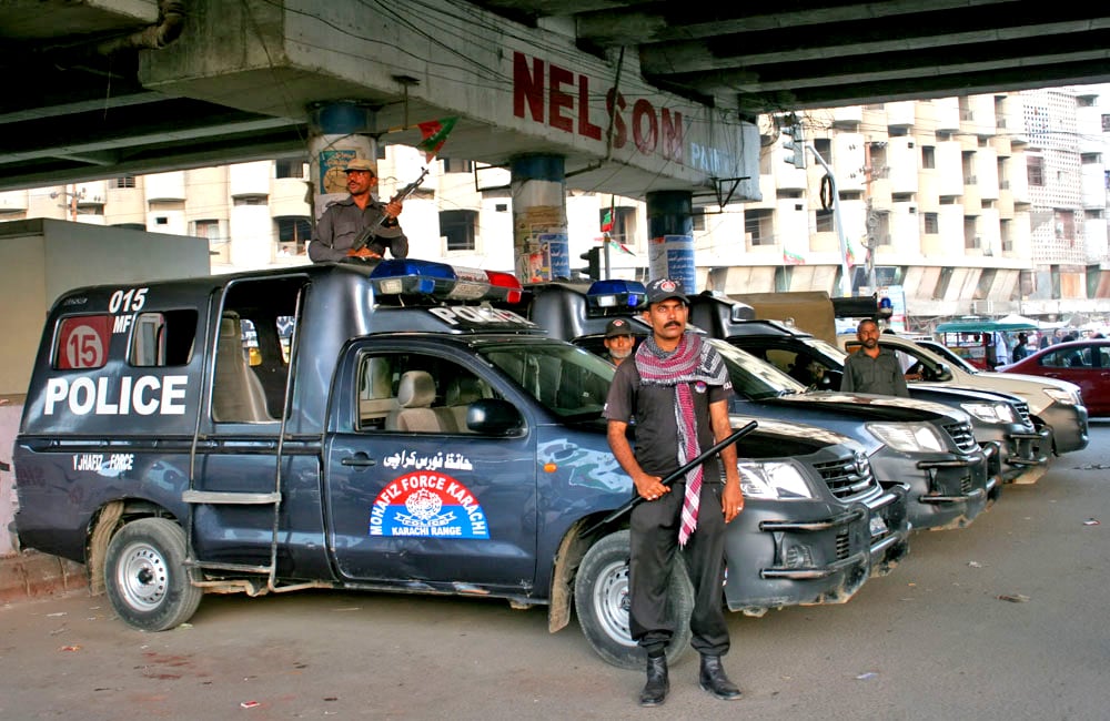 Karachi police officers standing beside a patrol vehicle.