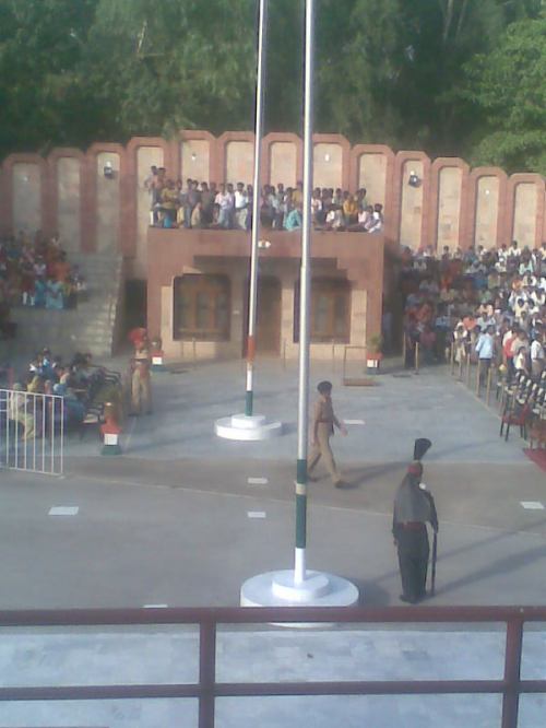 A flag-lowering ceremony at the Ganda Singh border in Kasur district, with border installations and spectators visible
