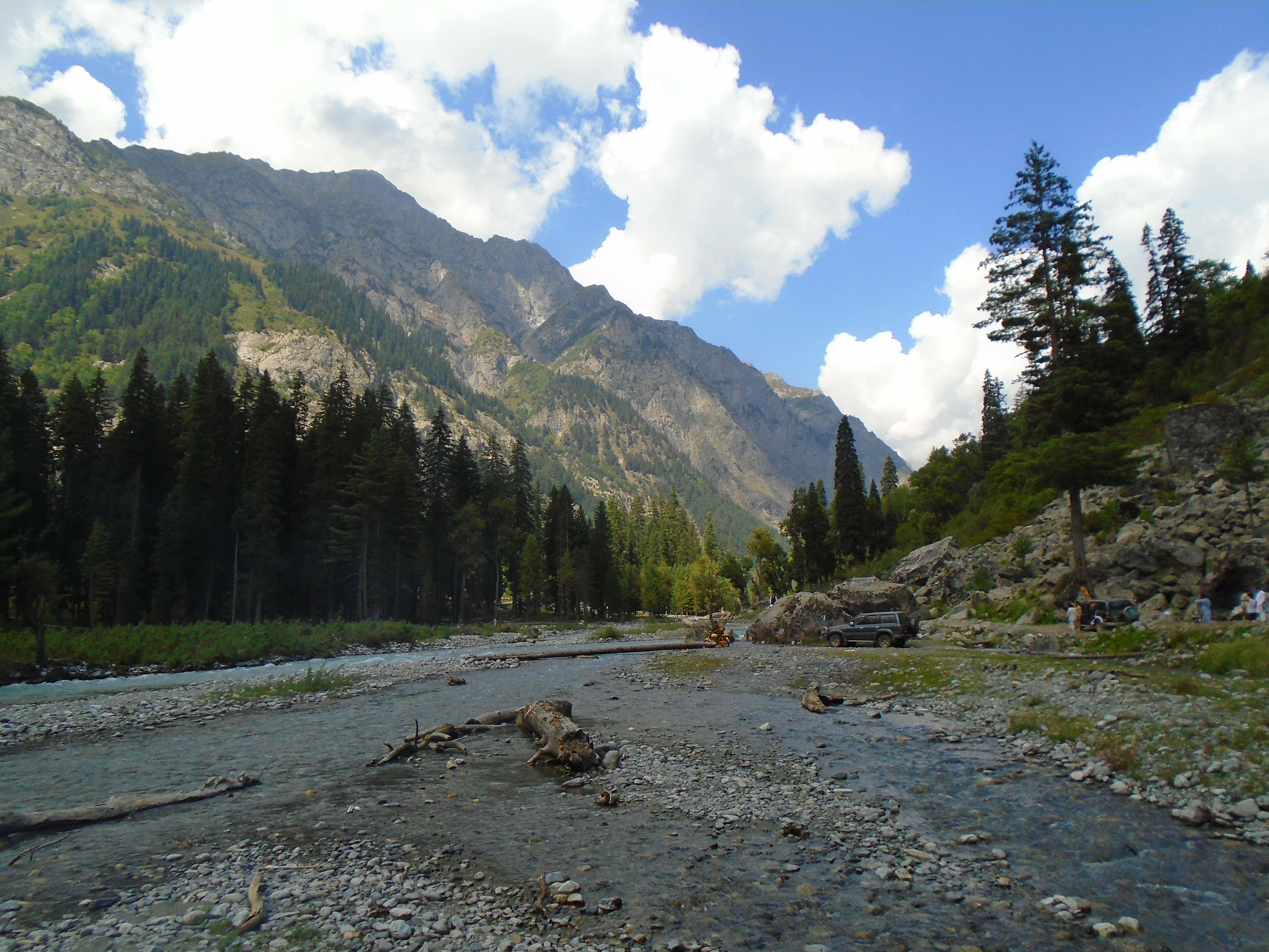 A wide landscape view of Kumrat Valley in Khyber Pakhtunkhwa showing forested hills and the river plain under a clear sky.