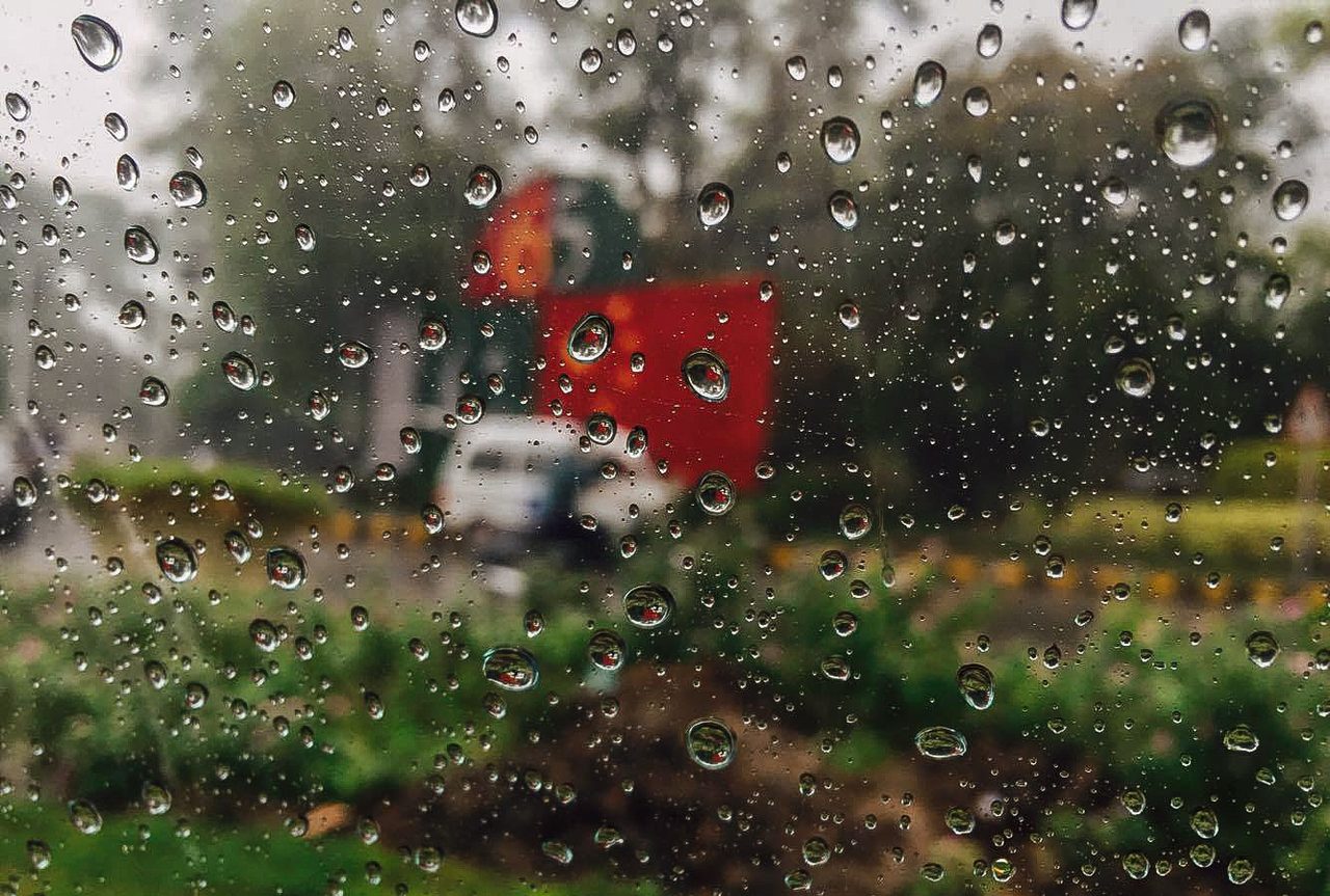 A wet street in Lahore under heavy rainfall with grey skies.
