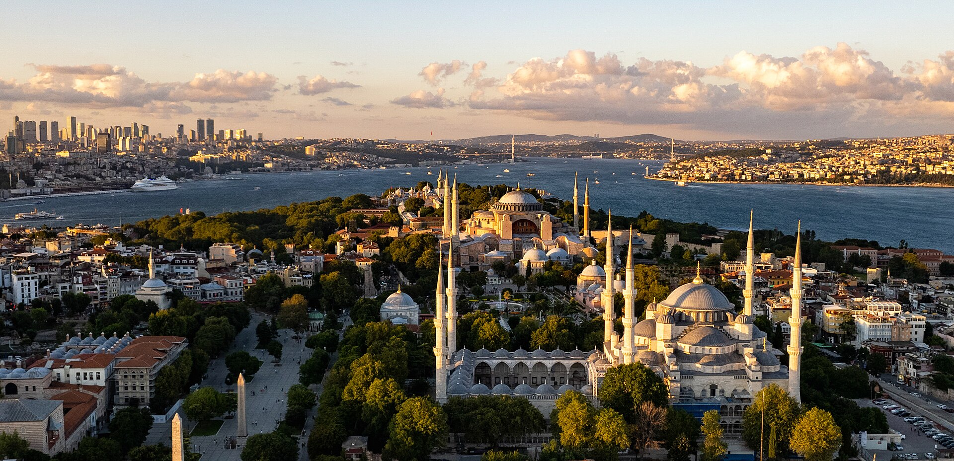 The Istanbul skyline across the water at dusk, with a historic mosque and minarets on the left and denser modern buildings to the right.