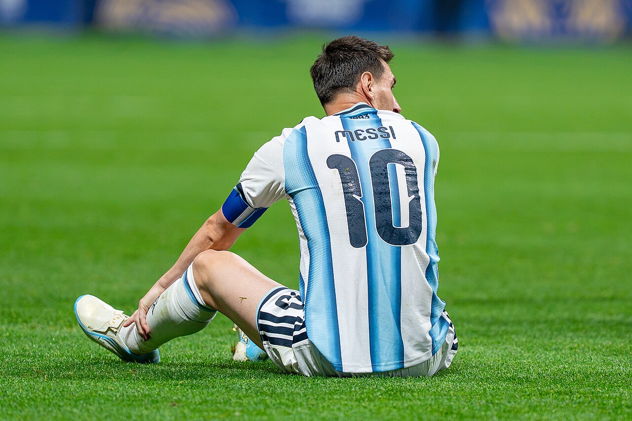 Lionel Messi in the Argentina national team jersey during a 2026 FIFA World Cup group stage match, photographed from the stands with crowd in the foreground.