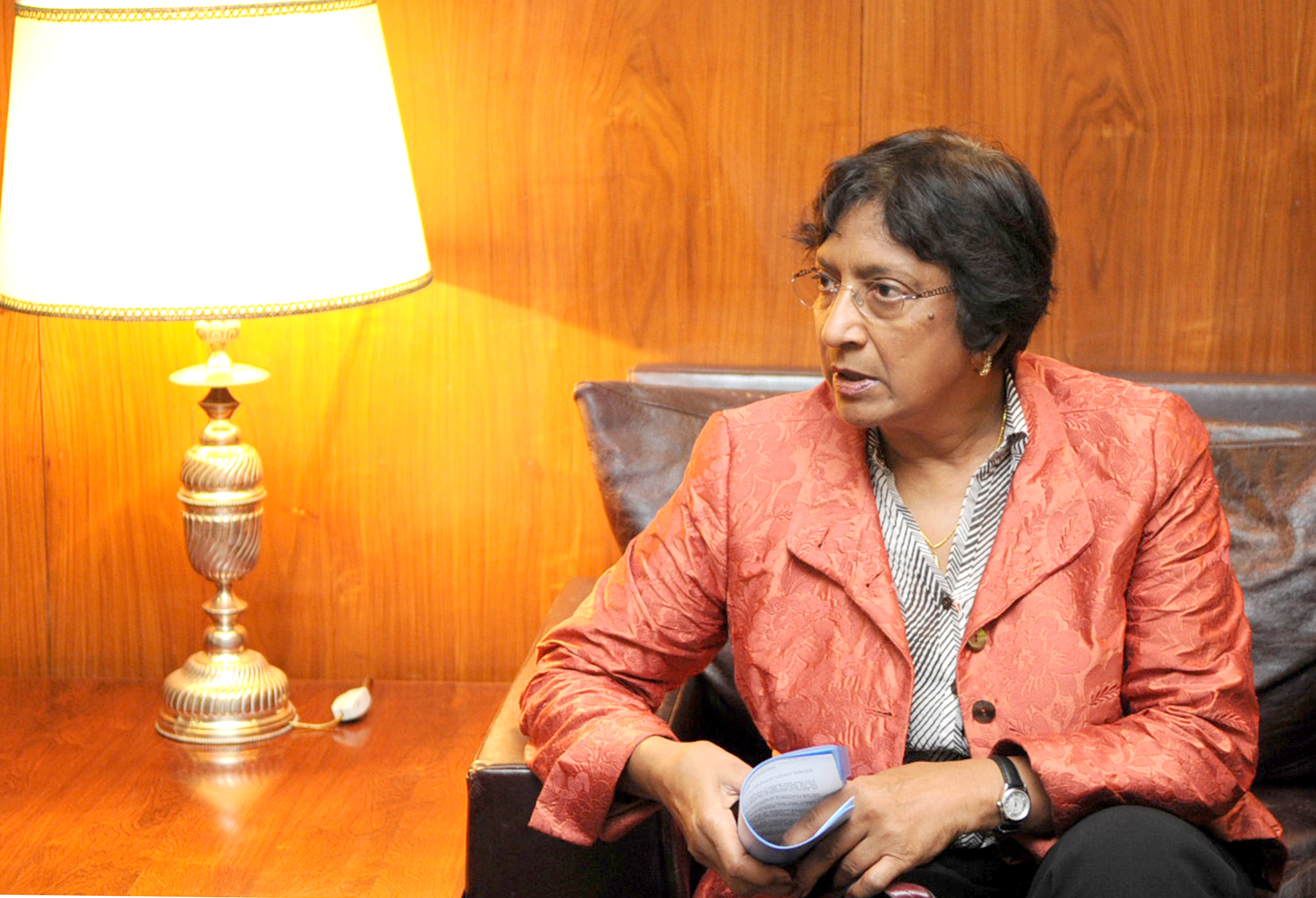 Navi Pillay, wearing glasses and a patterned orange jacket, seated and holding a document during a 2009 visit to Brazil.