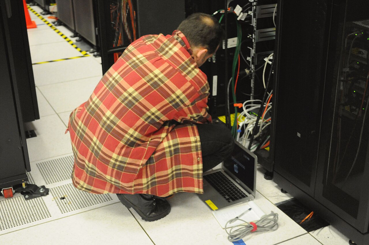 A technician works on a server rack in a data centre.
