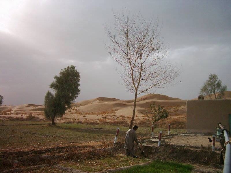 Farmland with a small settlement and low hills in Nushki District, Balochistan