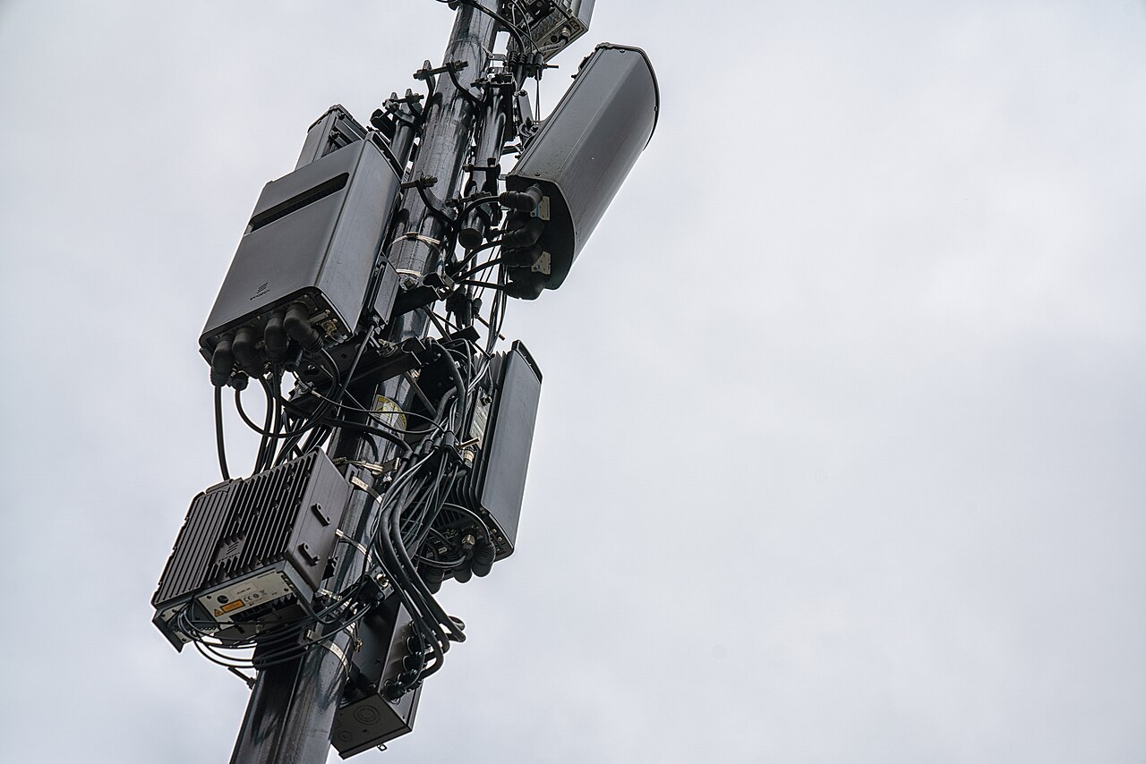 Three white cellular panel antennas mounted on a rooftop in Minneapolis, Minnesota, operating as 5G network equipment.