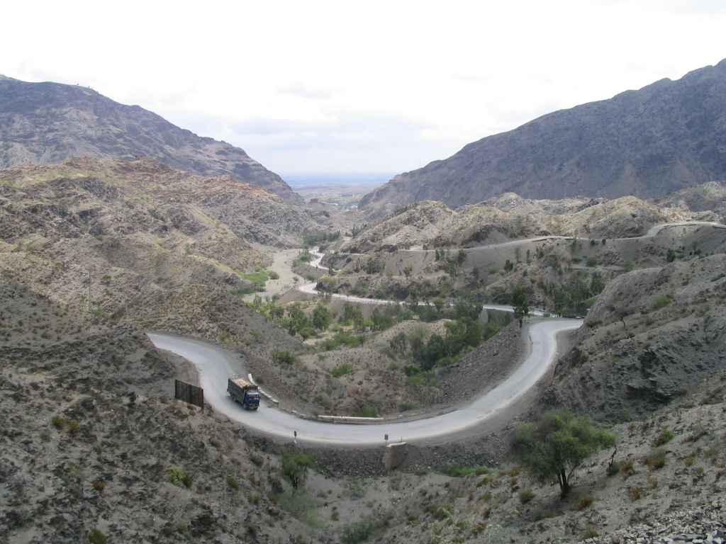 A winding road climbs through the dry, rocky hills of the Khyber Pass toward the Pakistan-Afghanistan border.