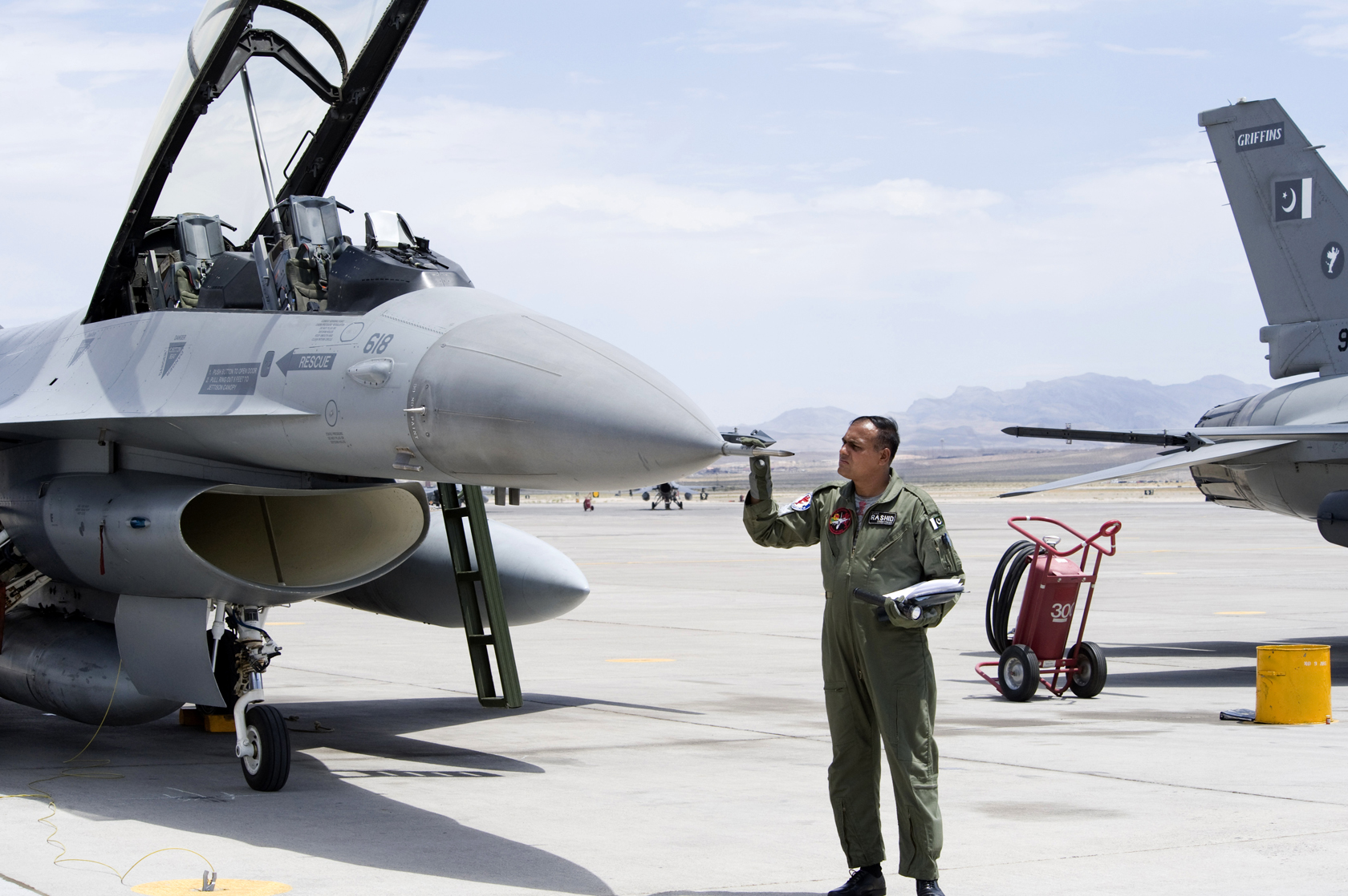 A Pakistan Air Force F-16 fighter jet with ground crew during a refuelling stop