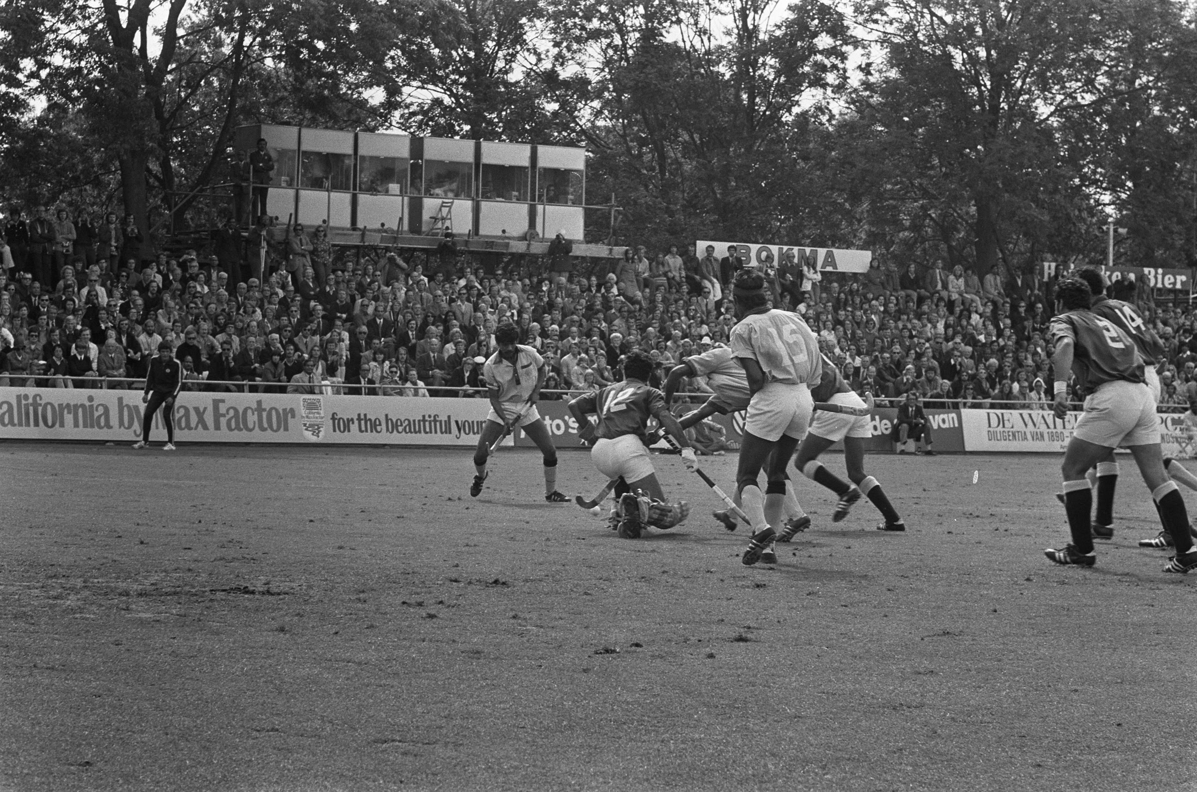 Black-and-white action photograph of India and Pakistan players contesting a field hockey match in 1973, with a packed grandstand behind