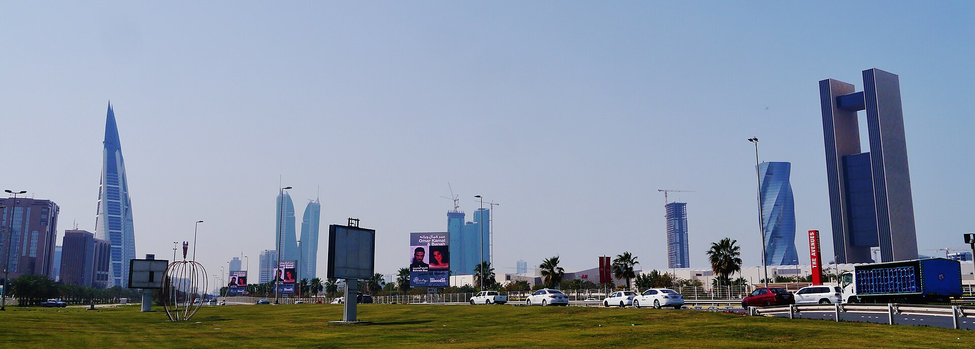 Daytime panorama of the Manama skyline in Bahrain, showing high-rise towers along the waterfront.