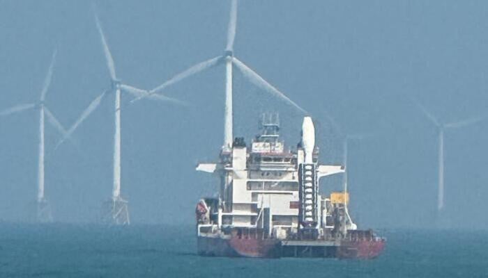 A seaborne launch platform at sea with wind turbines standing in the background off China's coast