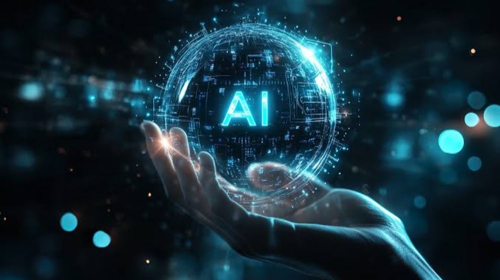 A glowing blue sphere bearing the letters AI, surrounded by circuit-like patterns, rests on an open hand.