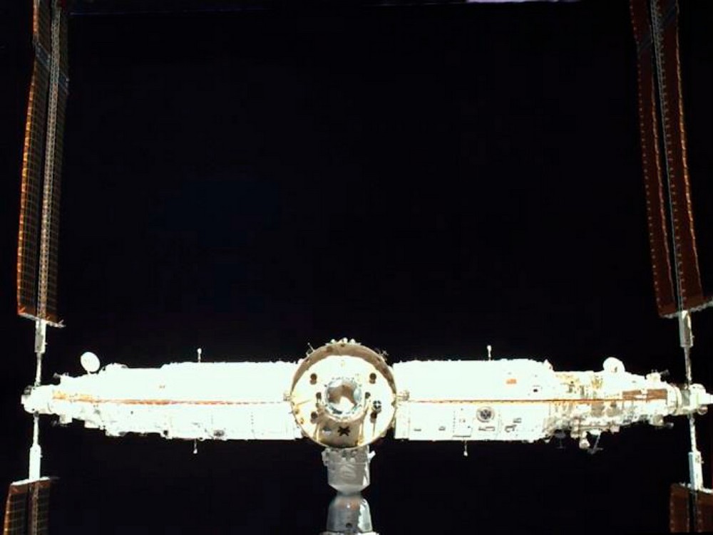 Rear view of China's Tiangong space station, with its cylindrical modules in a horizontal row and solar arrays extending to both sides against black space