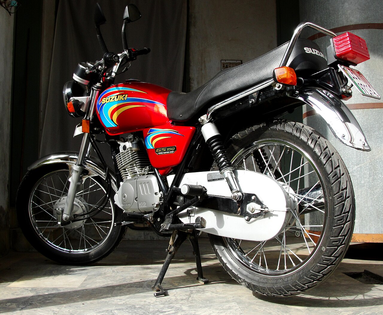 A parked Suzuki GS-150 motorcycle on a street in Lahore, Pakistan
