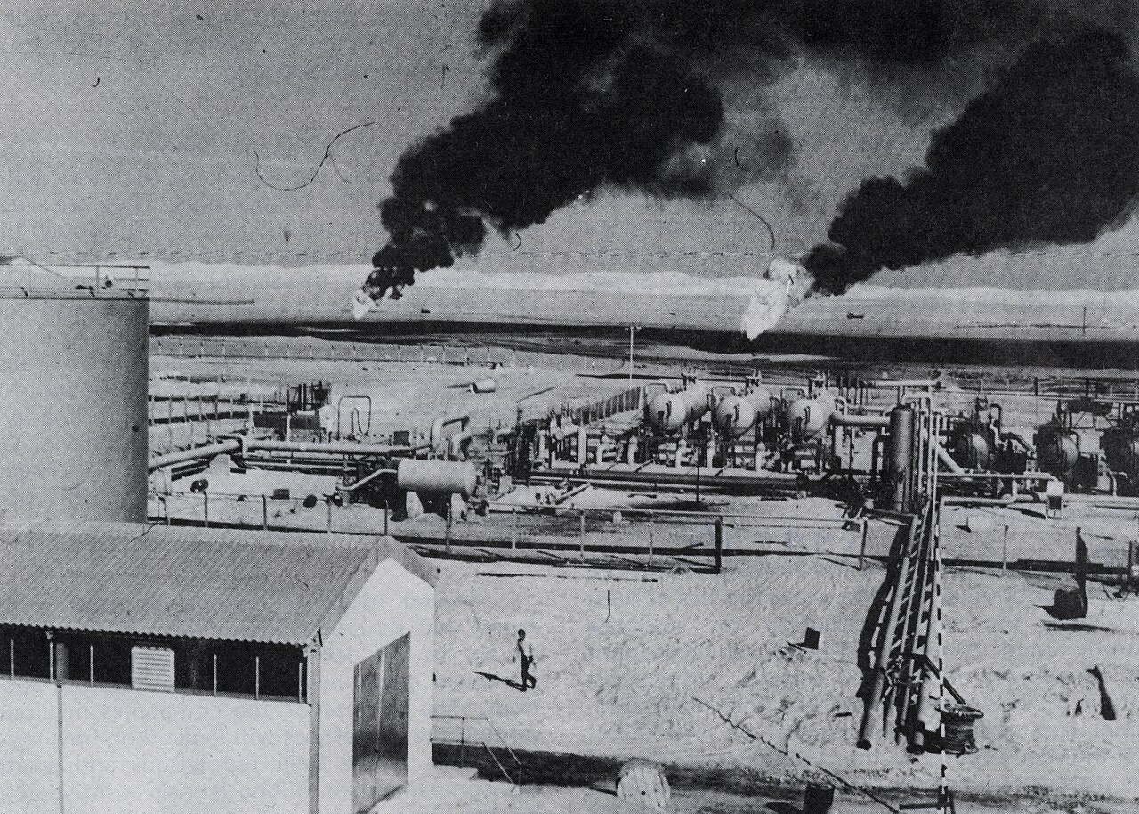 A Libyan oil facility seen from the air, with a cluster of tanks and pipelines against a desert landscape.