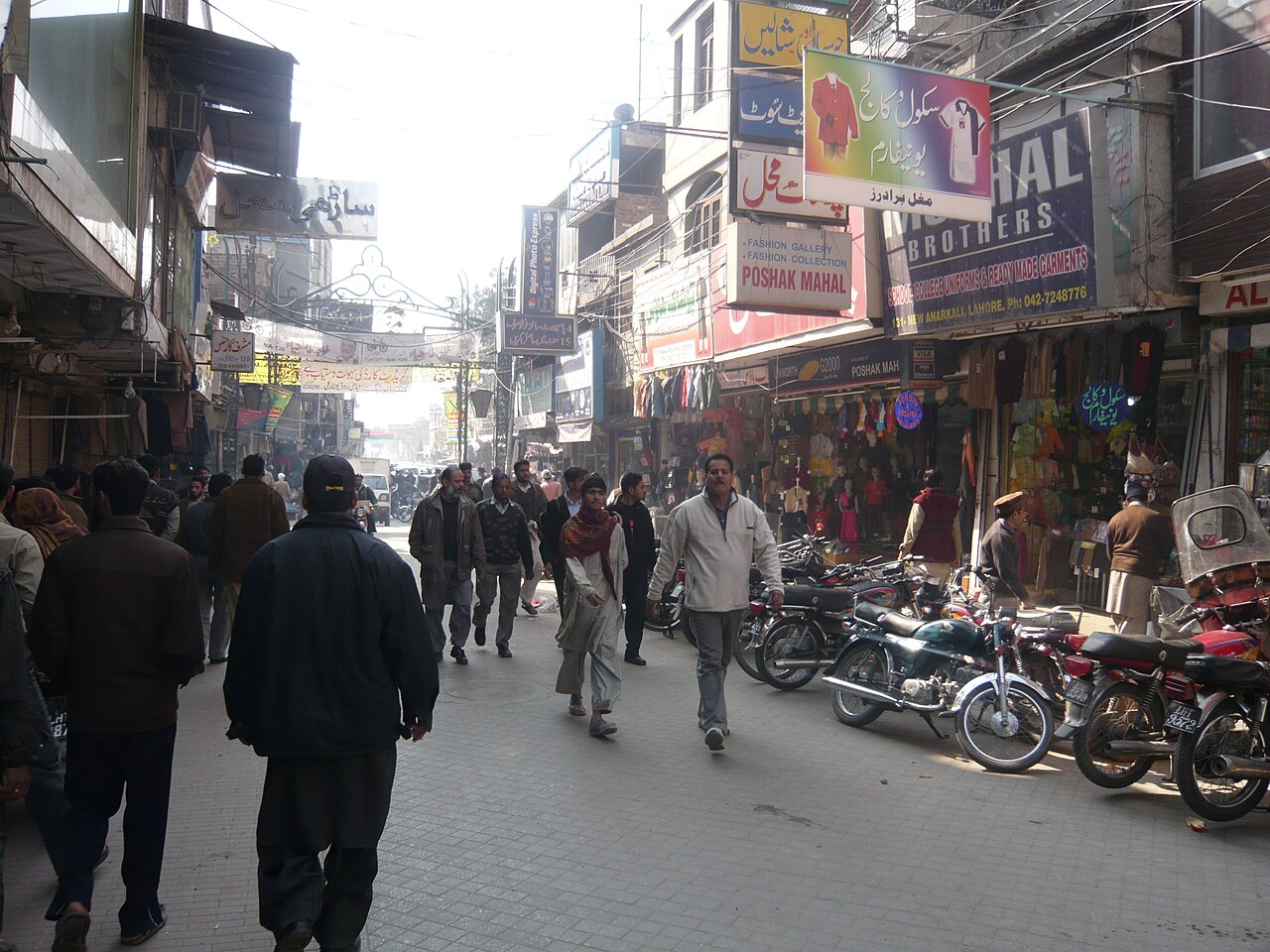 Shoppers and pedestrians walking past small shops in the Anarkali bazaar in Lahore, Pakistan.