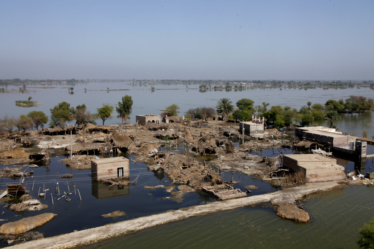 Flood-damaged buildings and shallow standing water in a village after monsoon flooding in Sindh, Pakistan.