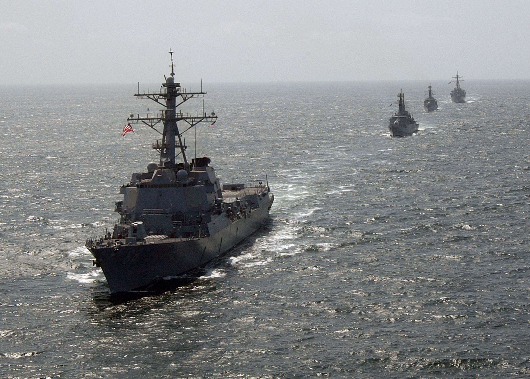 Two naval destroyers sailing in column formation on open water