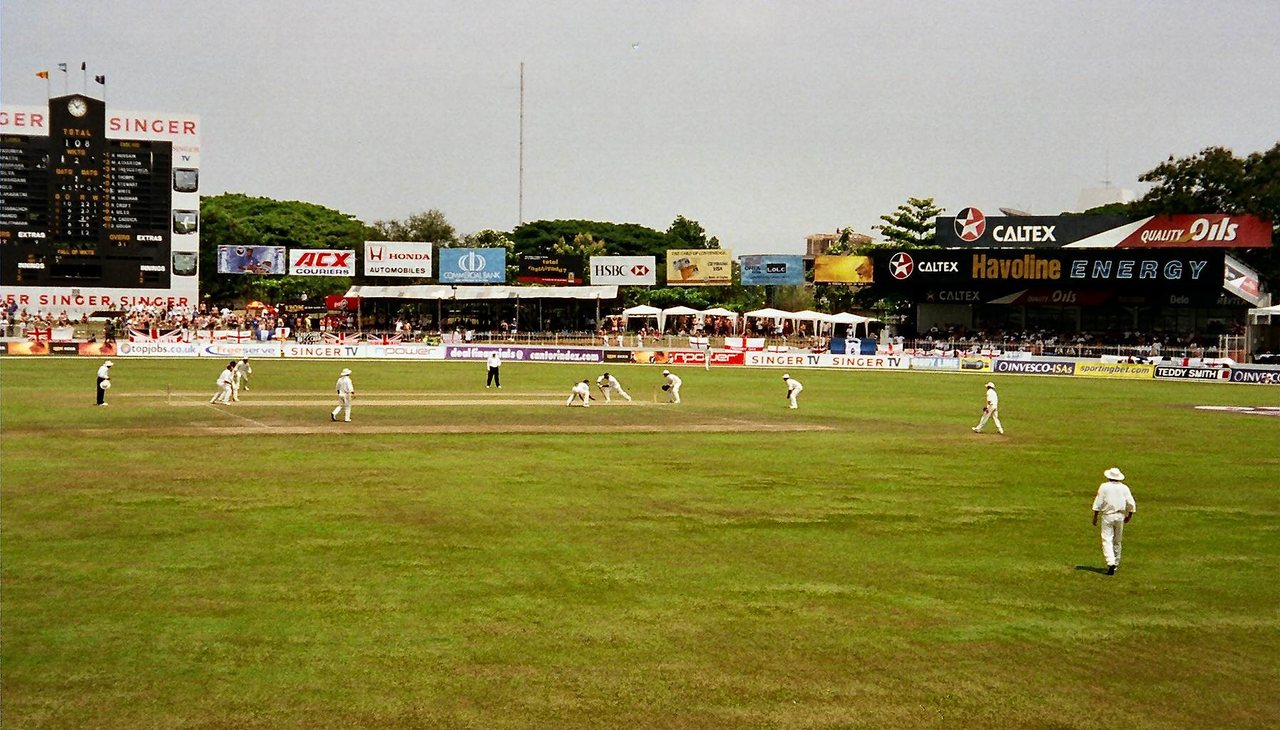 A cricket ground in Colombo with a green outfield, white sight screens and a pavilion in the background