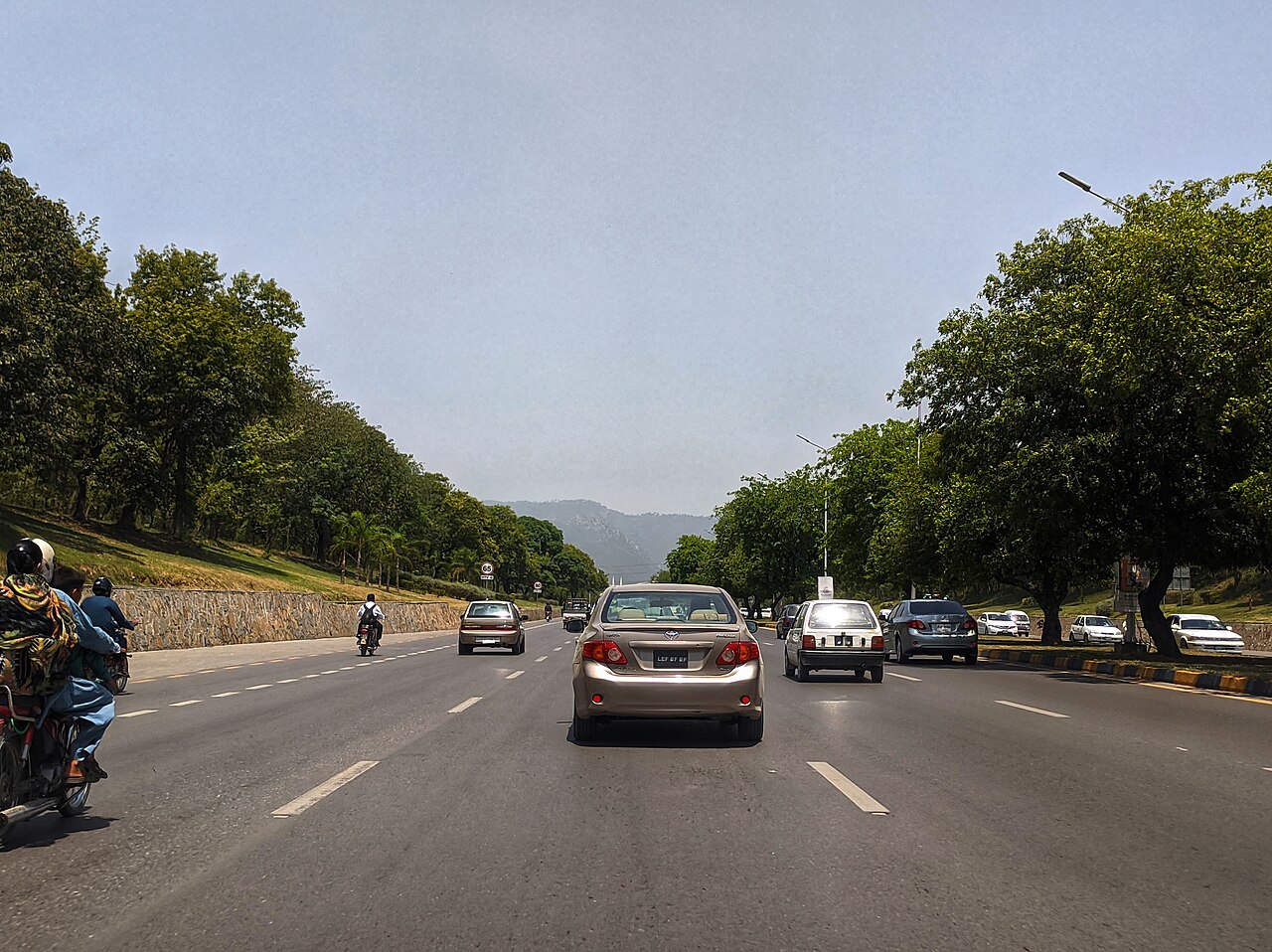 A multi-lane road in Islamabad with vehicles and overhead signage.