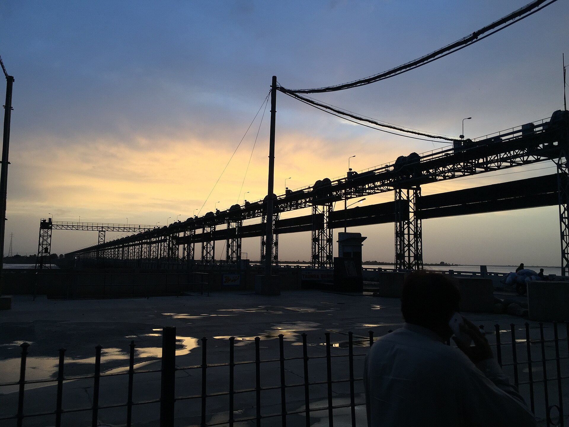 The Indus River flowing past the Taunsa Barrage in Punjab under a sunset sky, with water spread across the barrage structure.