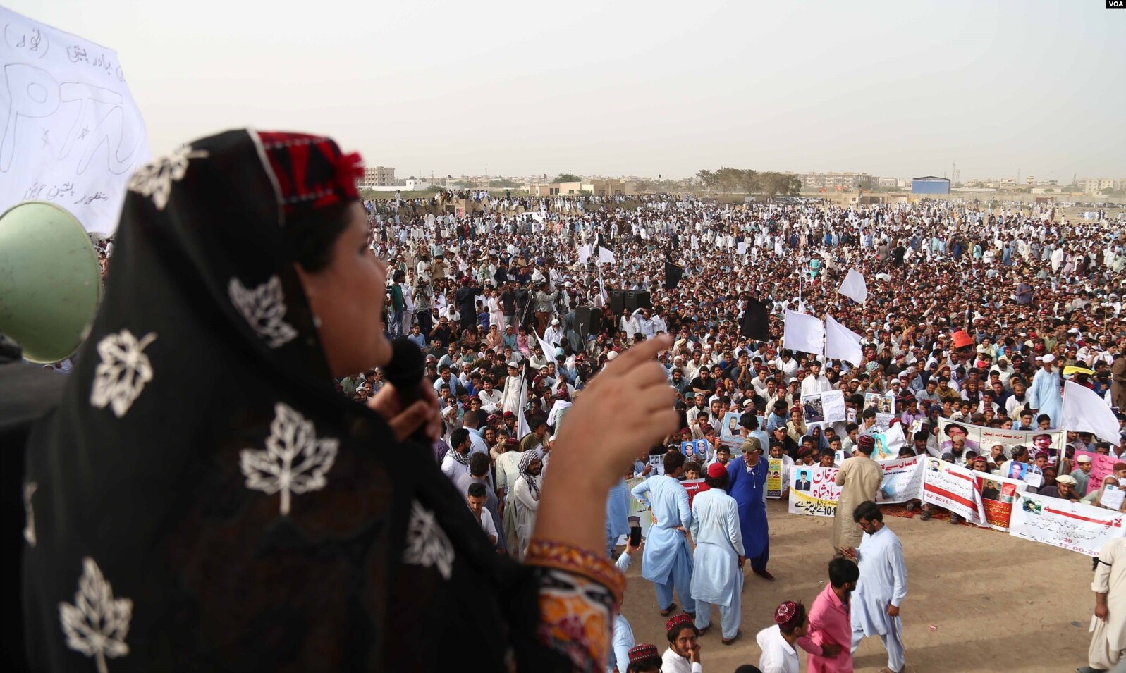 Crowd of protesters gathered at a road junction in Karachi with flags and banners raised during a demonstration.