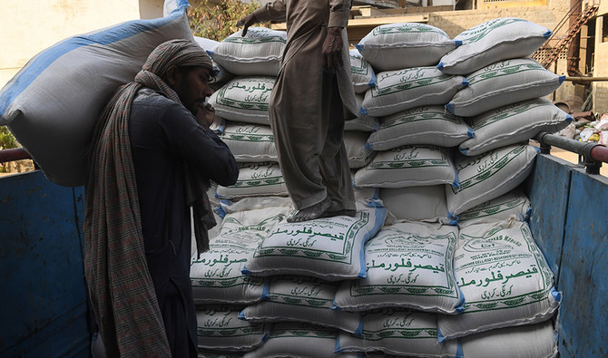 Workers loading sacks of wheat flour onto a truck at a depot.