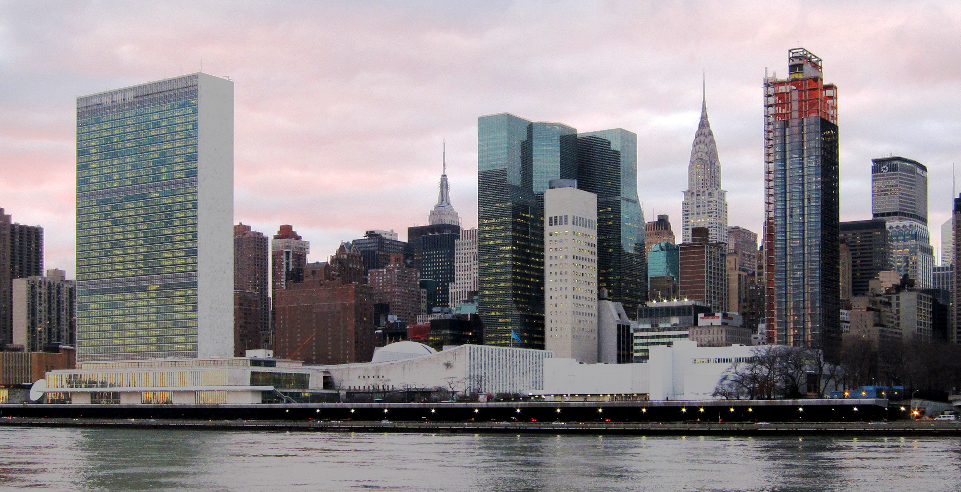 The United Nations Headquarters complex in New York seen from across the East River, with the Secretariat tower and the General Assembly building on the waterfront