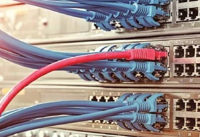A telecoms worker inspecting fibre-optic and submarine cable equipment at a network facility.