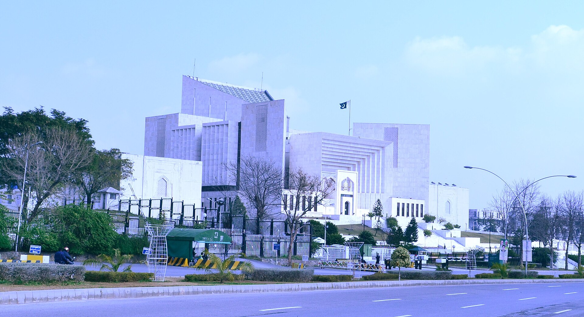 The Supreme Court of Pakistan building in Islamabad, a white structure with a large central dome and columns, seen under a clear sky.