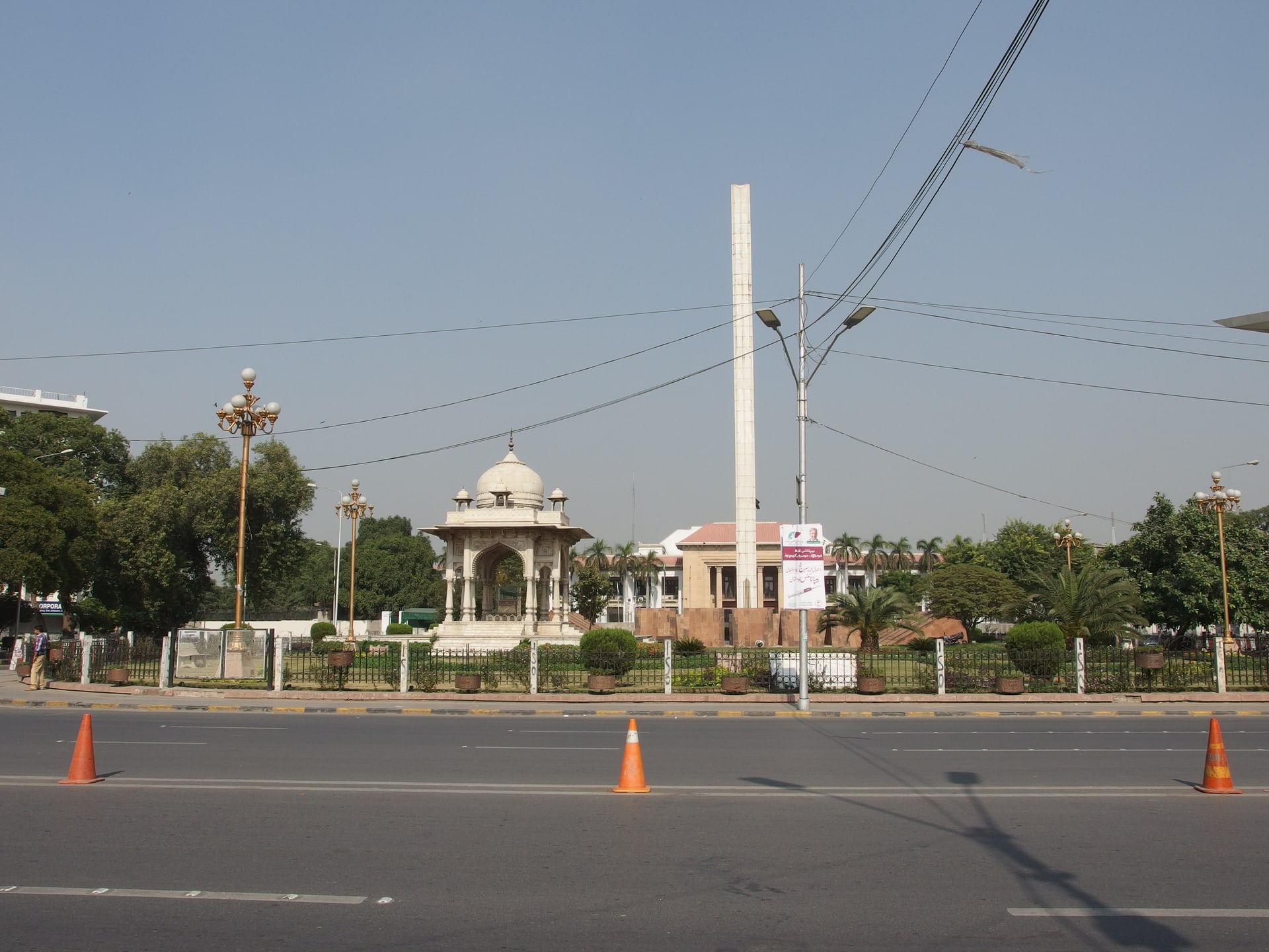 The multi-storey Punjab Assembly building on The Mall in Lahore, seen from the roadside with trees and passing traffic in the foreground.