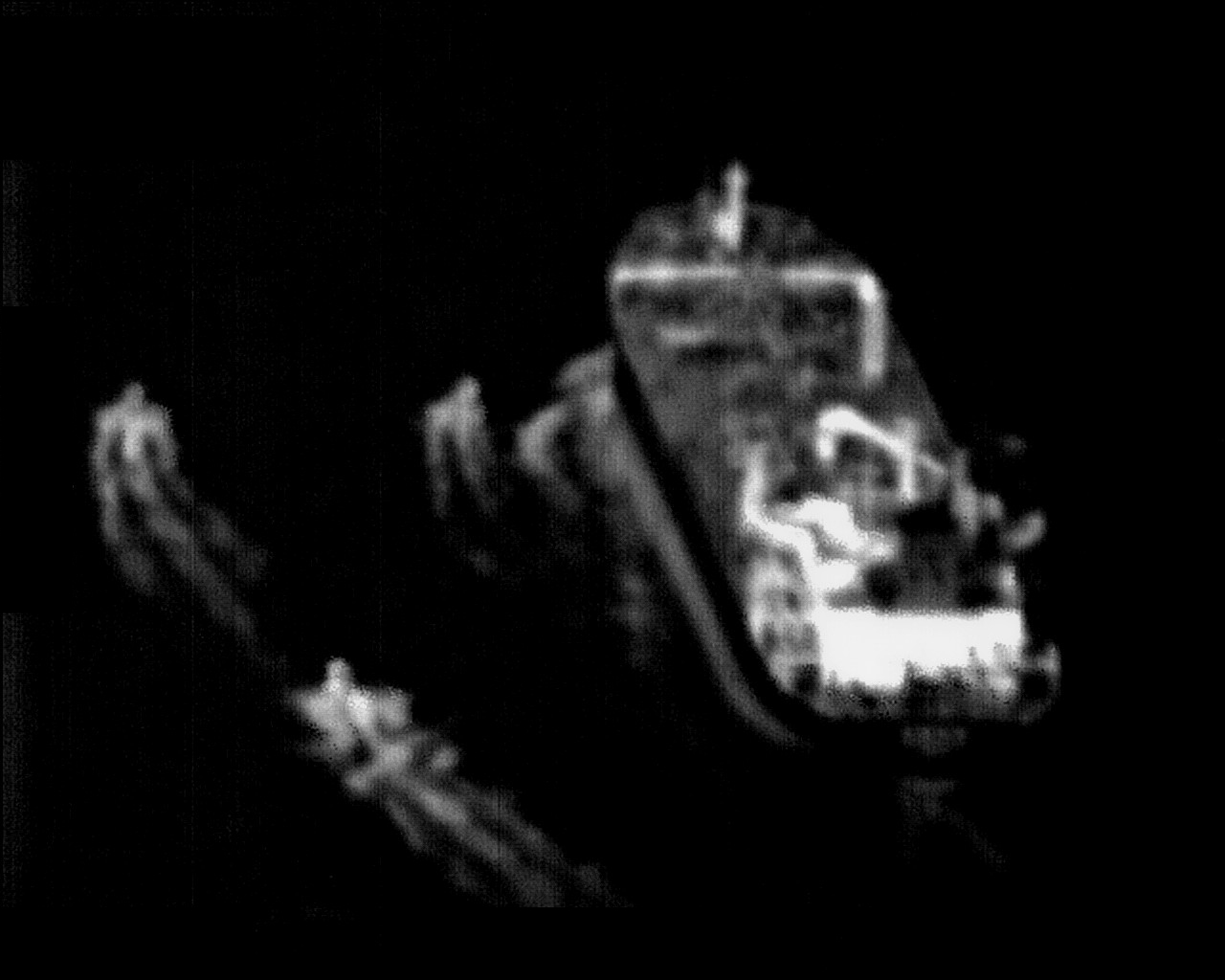 Grainy surveillance-camera still showing three small fast-attack craft closing on a larger merchant vessel on open water.