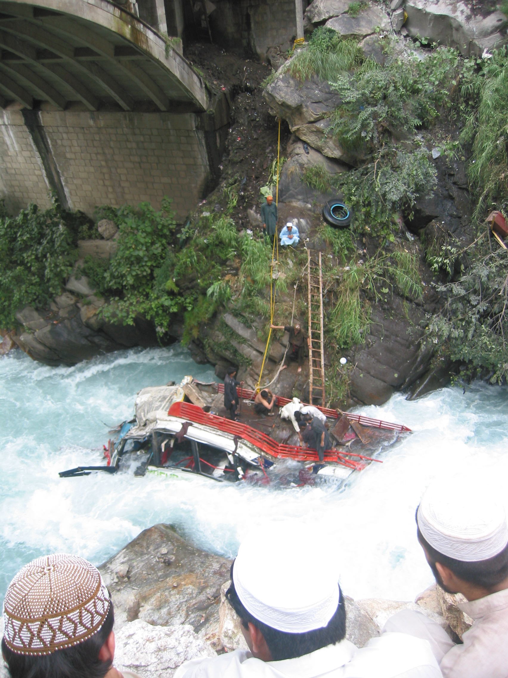 An overturned passenger bus beside a hill road in a mountainous stretch of northern Pakistan, seen in an August 2004 archival photograph.
